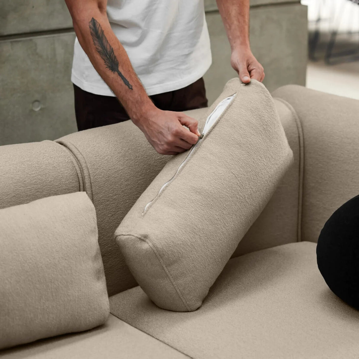 Premium beige boucle sofa with removable cushions, featuring a sleek zip design. Set in a modern concrete interior, exuding luxury and comfort.
