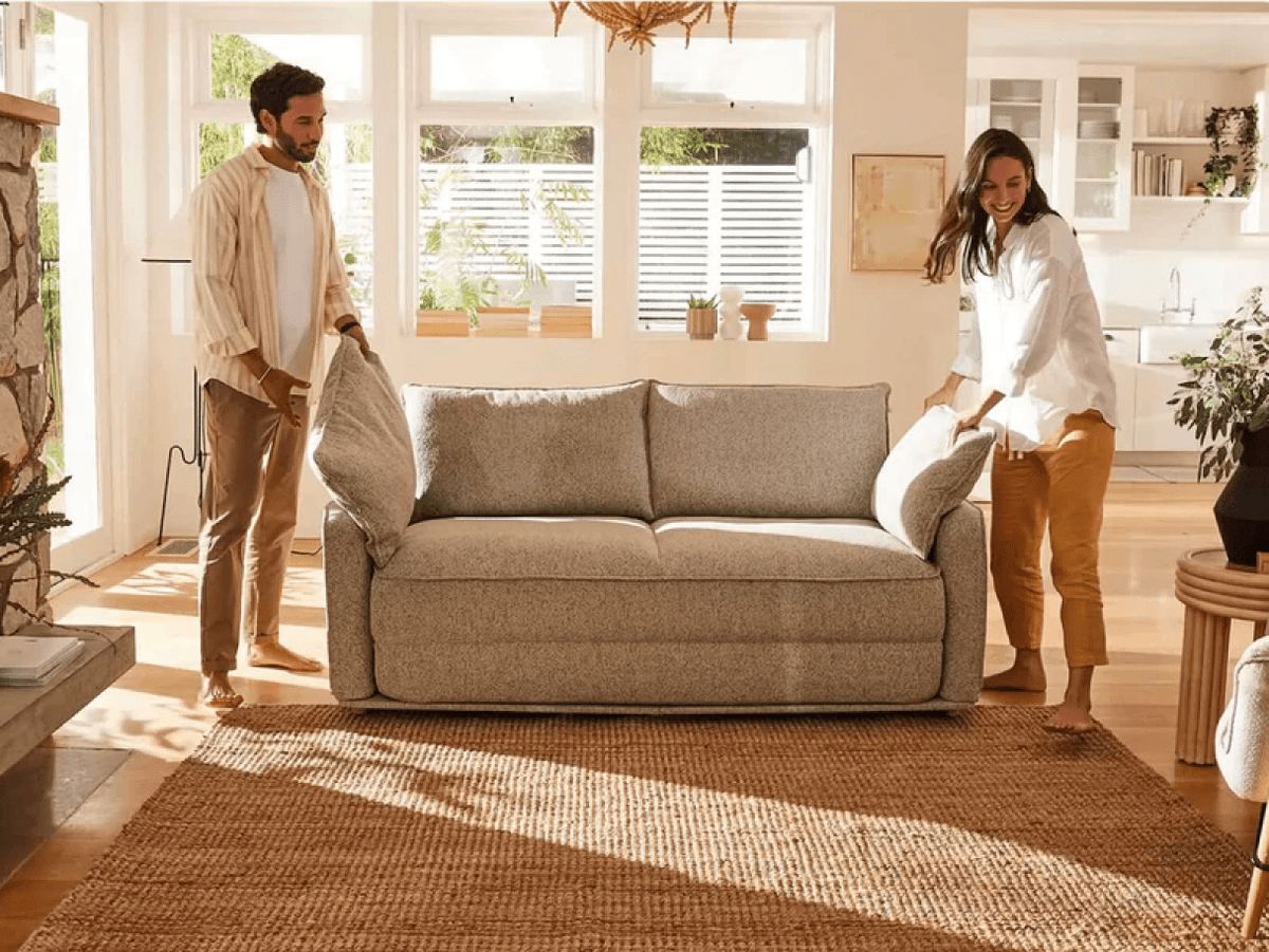 Luxurious grey linen sofa, plush and inviting, with removable cushions. Situated in a sunlit living room with wooden flooring and contemporary decor.