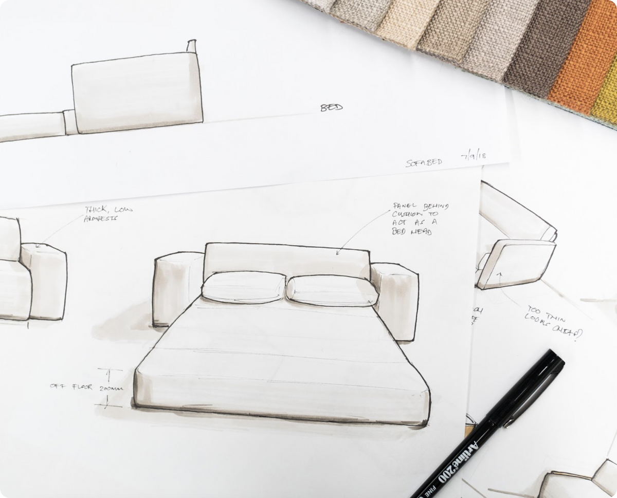 Sketches of a light beige sofa design with a bed feature and labeled notes, alongside a color swatch of warm tones. A black pen is nearby.