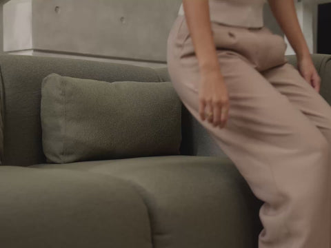 a woman sitting back on an olive green Bangalow modular sofa showing how comfortable and relaxing the sofa is.
