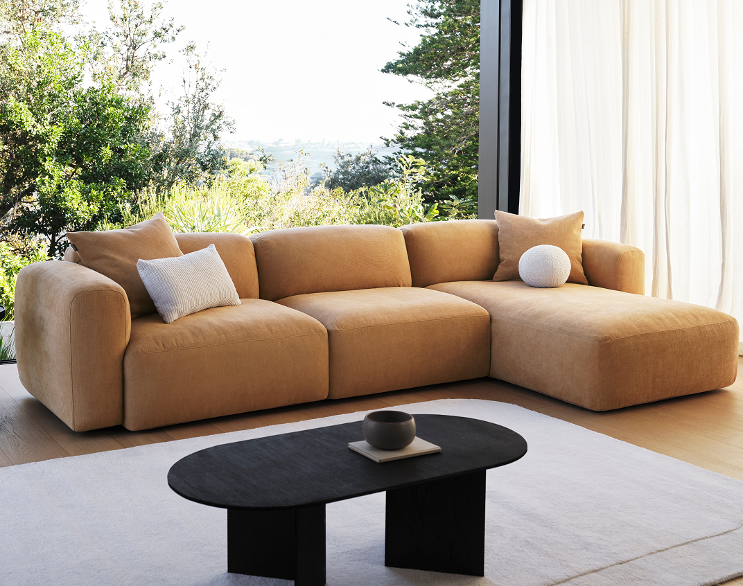 Beige sectional sofa in a modern living room with a coffee table and decorative items.